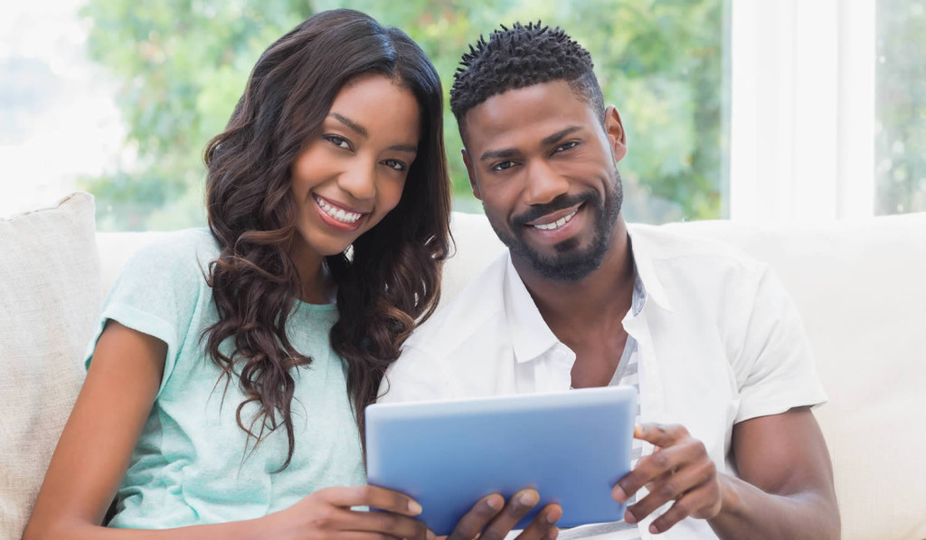 Attractive couple engaging with their tablet results at home, London City Mortgages