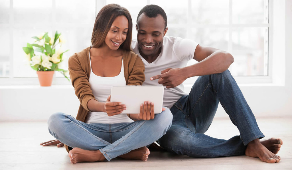 Attractive couple relaxing at home engaging with their tablet notices, London City Mortg