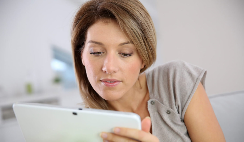 Cheerful women on the sofa accessing her tablet updates, London City Mortgages