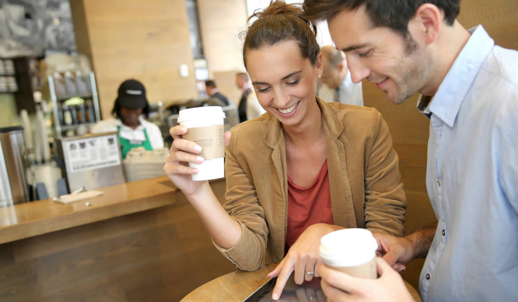 Couple accessing their tablet notices in a coffee shop, London City Mortgages