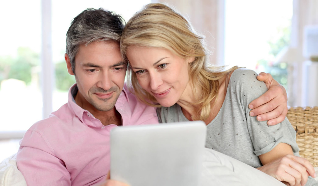 Couple at home reading pages on their tablet, London City Mortgages