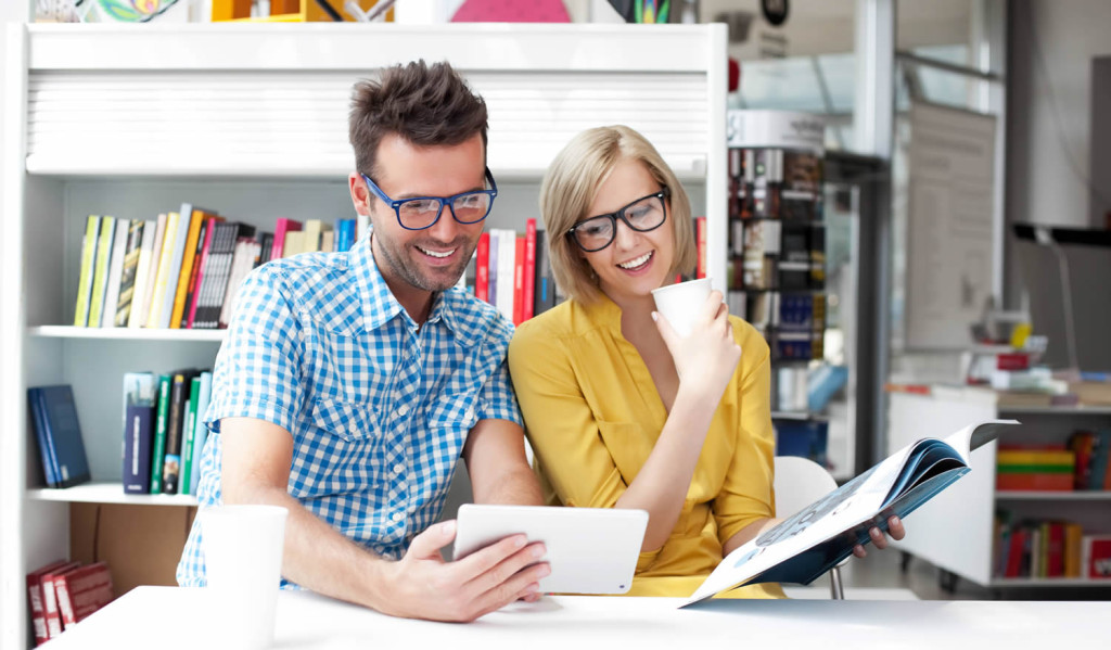 Couple in a library receiving their tablet news, London City Mortgages