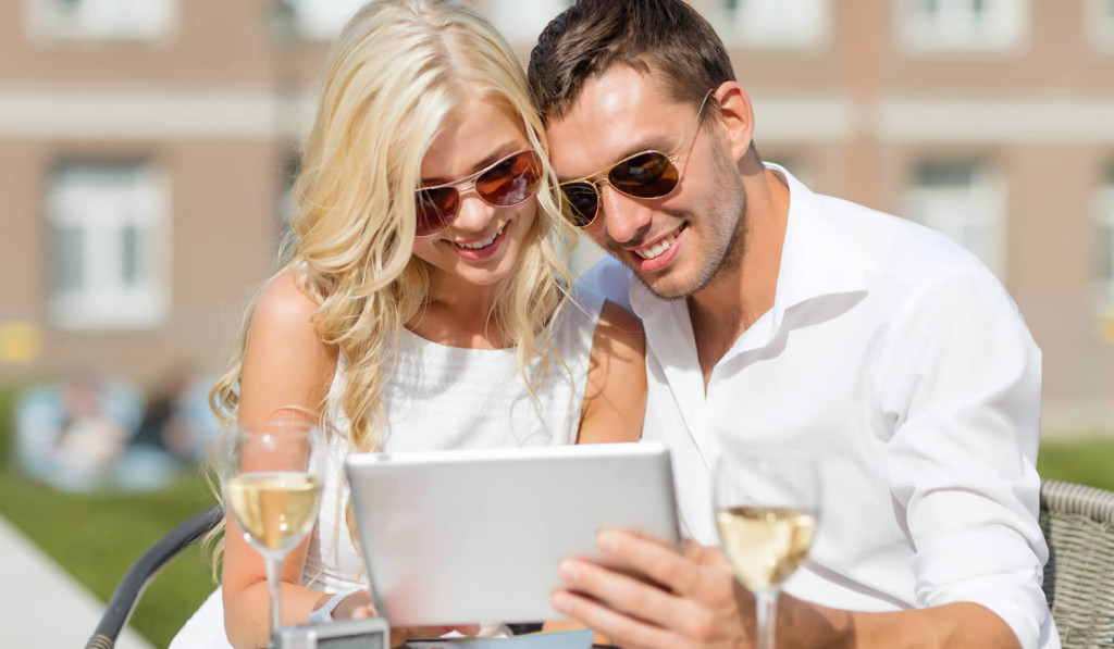 Couple relaxing and drinking wine while viewing tablet updates, London City Mortgages