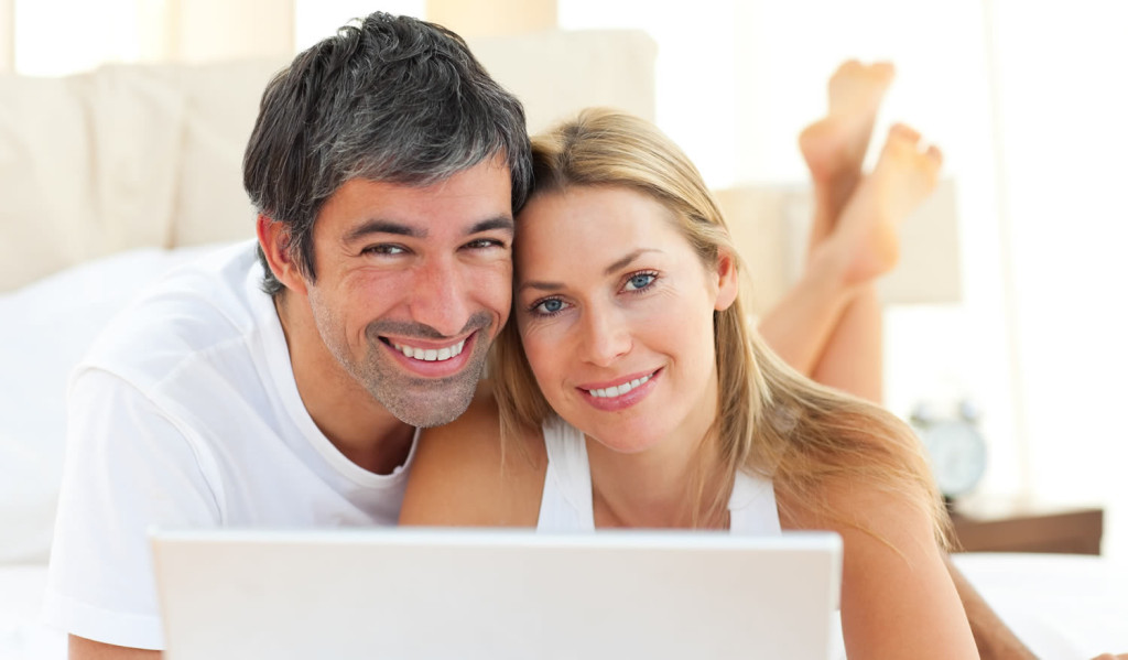 Happy couple at home receiving laptop updates, London City Mortgages