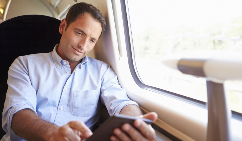 Man viewing his tablet updates on a train, London City Mortgages