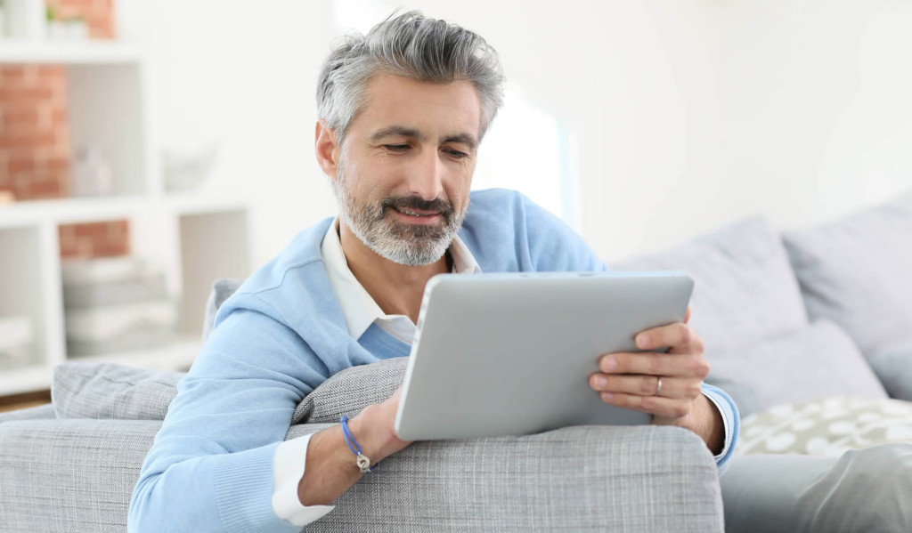 Mature man relaxing in the livingroom accessing his notices, London City Mortgages