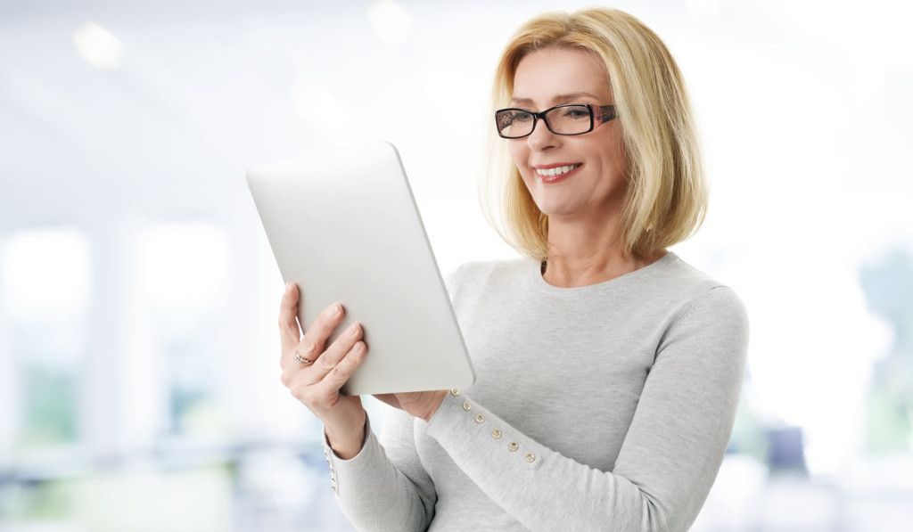 Mature woman at work engaging with her tablet updates, London City Mortgages