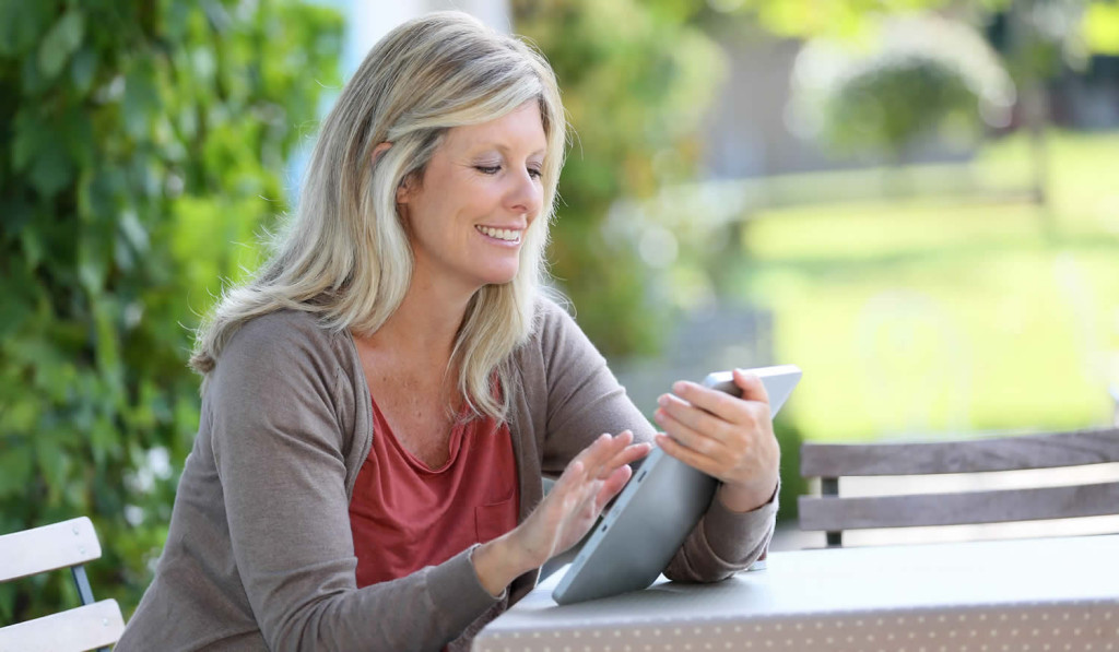 Mature women relaxing outdoors while using her tablet for updates, London City Mortgages