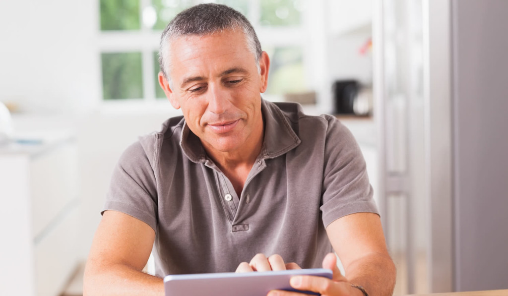 Middle age homeowner engaging with his tablet notices, London City Mortgages