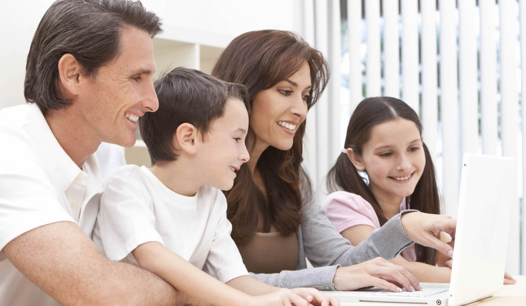 Smiling family of four using their laptop for updates, London City Mortgages