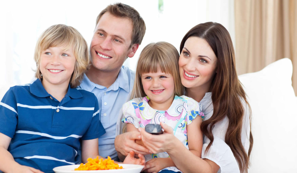 Smiling family watching a movie on their sofa, London City Mortgages