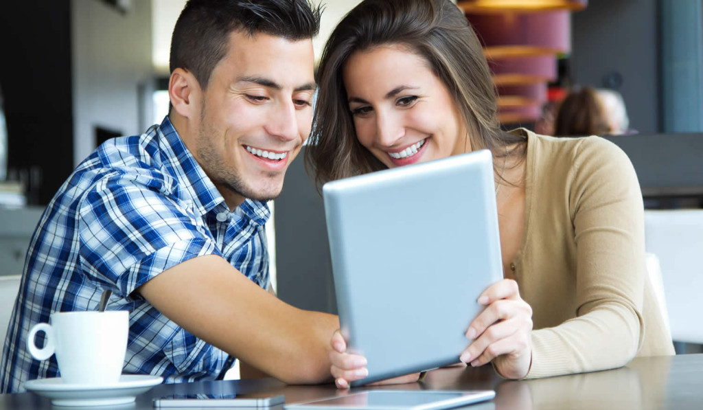 Smiling young couple in a cafe with their tablet updates, London City Mortgages