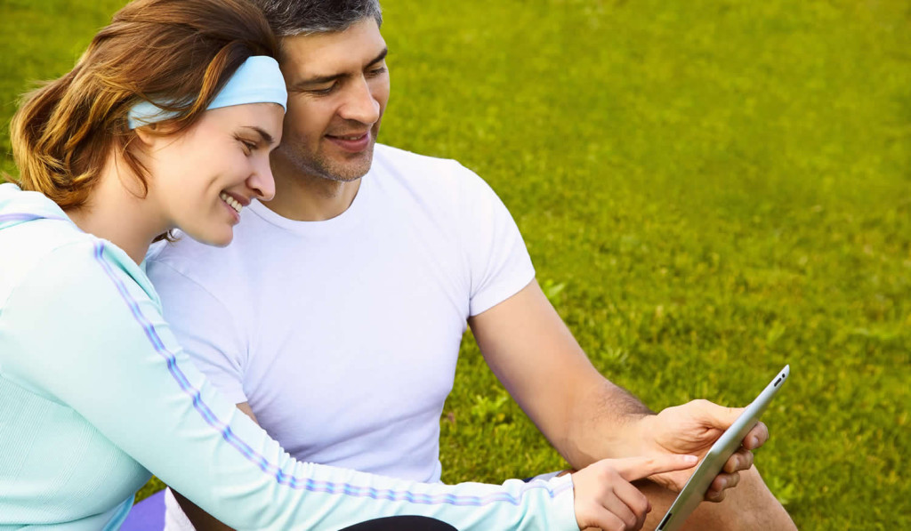 Sports couple in the park viewing tablet updates, London City Mortgages