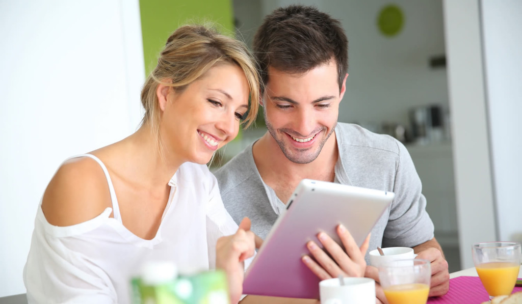 Young couple having breakfast receiving notices on their tablet, London City Mortgages