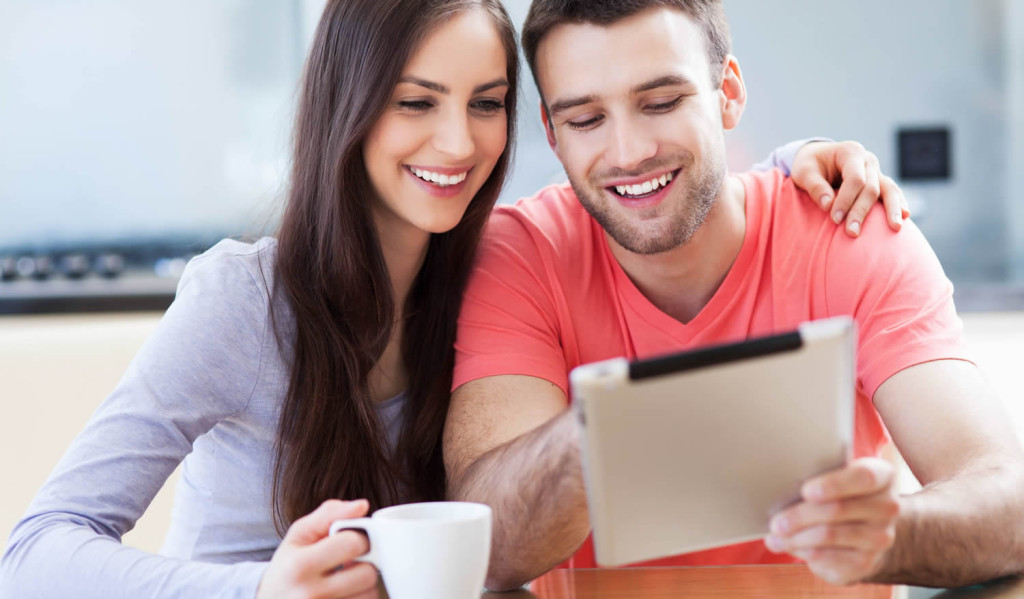 Young couple having coffee while engaging with their tablet results, London City Mortgages