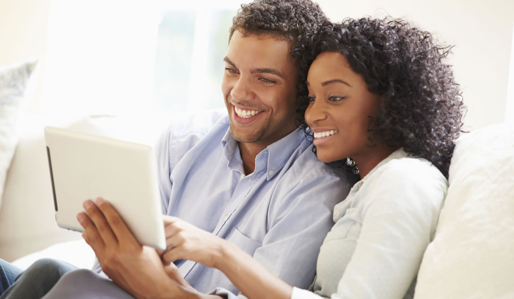 Young couple on a sofa accessing their tablet notices, London City Mortgages