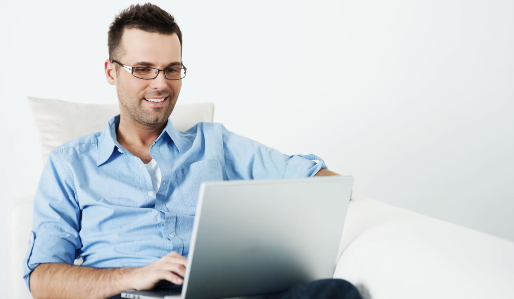 Young homeowner accessing updates on his laptop, London City Mortgages