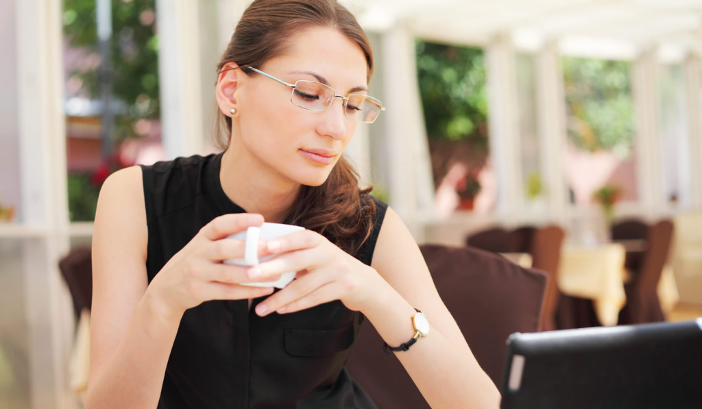 Young women looking at her tablet news while drinking coffee in a cafe, London City Mortgages