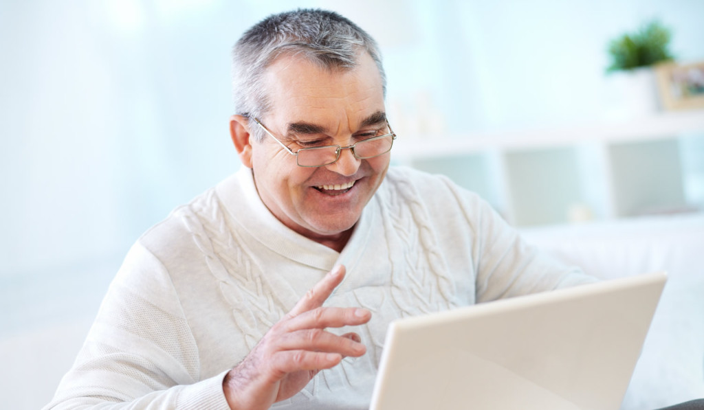 Delighted older man good news on laptop London City Mortgages