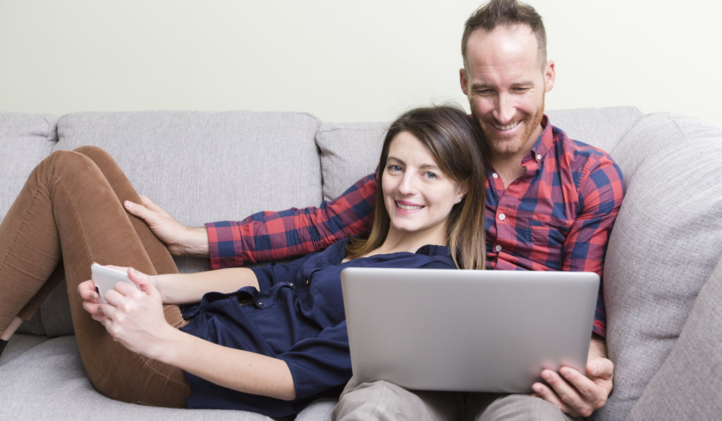 Lying on livingroom sofa couple on laptop London City Mortgages